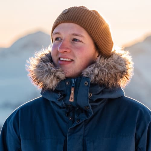 Julius in a winter jacket at sunset in the mountains