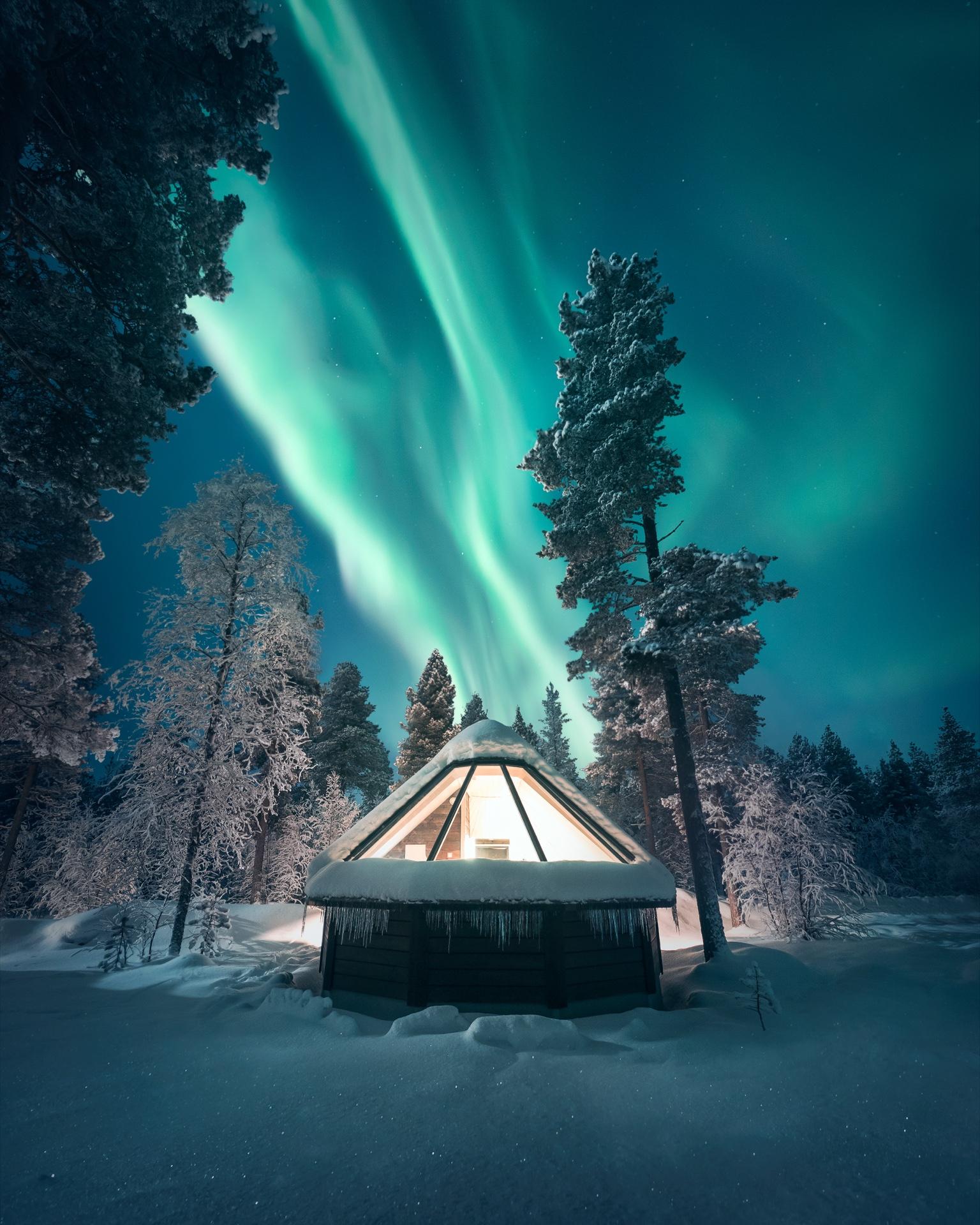 Our reel: a guest on the bed of an Aurora Village cabin, aurora outside